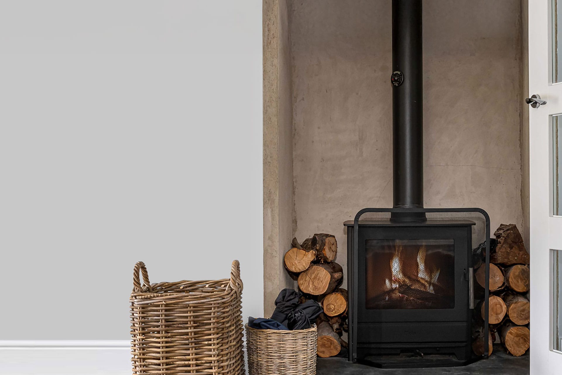 Log burner with stacked firewood and wicker basket in a holiday let by Red Kite Hosts