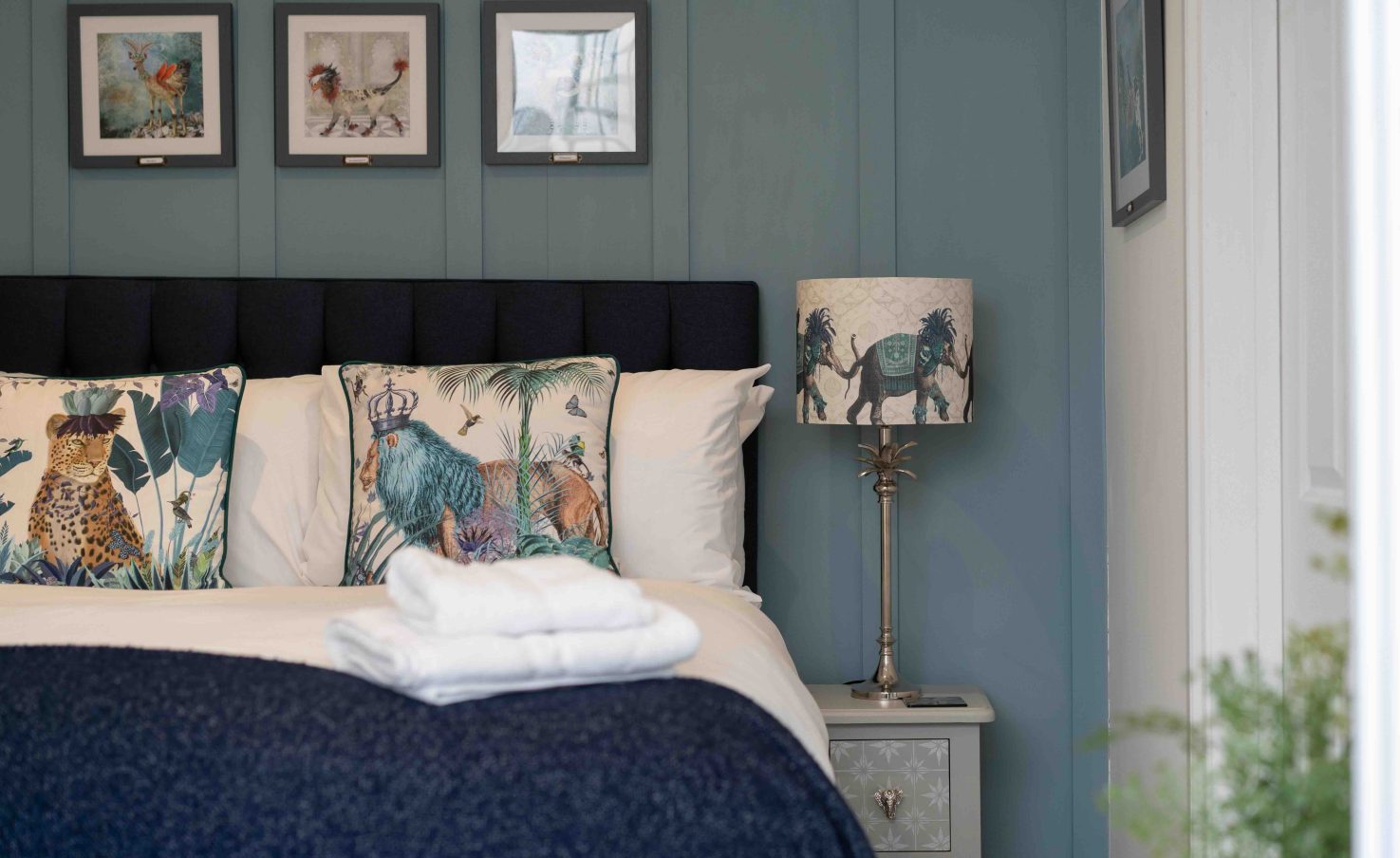 Styled double bedroom with nature-print cushions, animal lamp and framed artwork in a holiday let managed by Red Kite Hosts