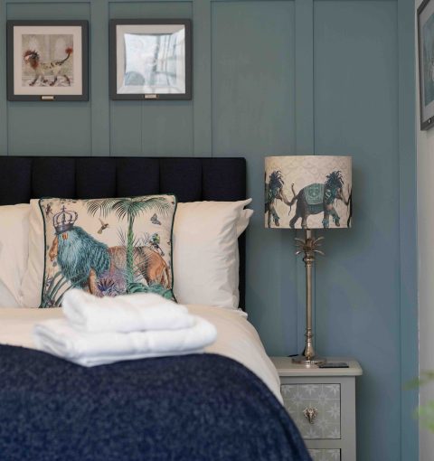 Styled double bedroom with nature-print cushions, animal lamp and framed artwork in a holiday let managed by Red Kite Hosts
