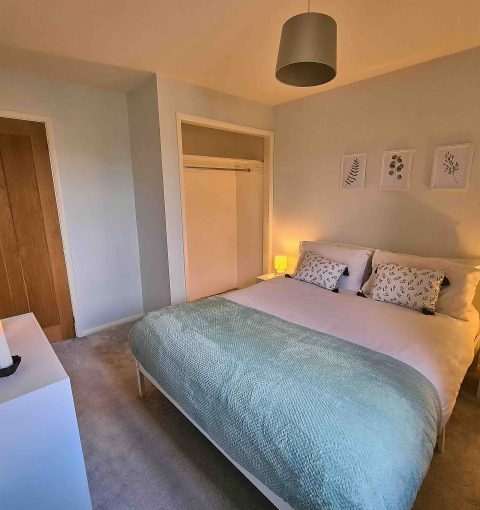 Cosy double bedroom with soft lighting, fresh flowers and neutral decor in a holiday let managed by Red Kite Hosts